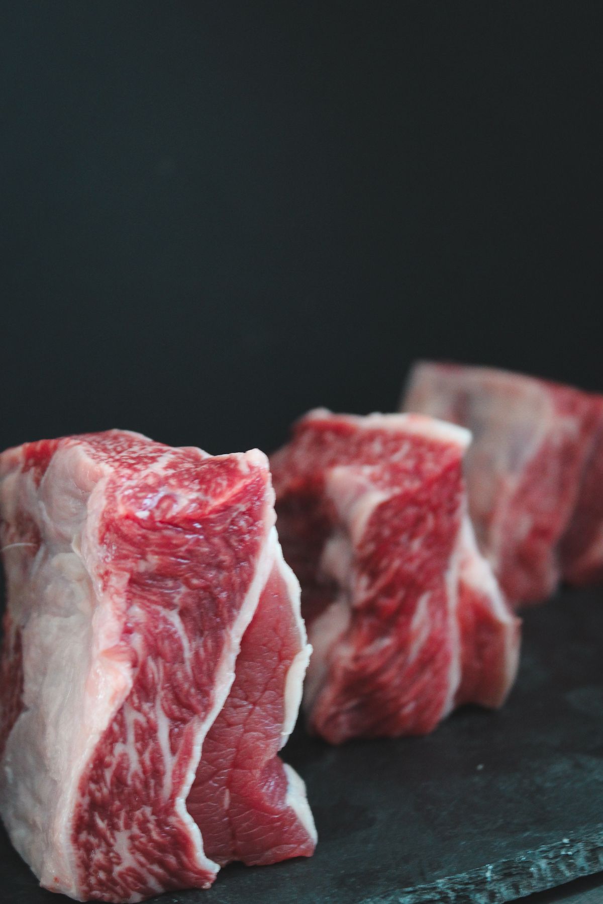 Raw beef cuts on a dark surface