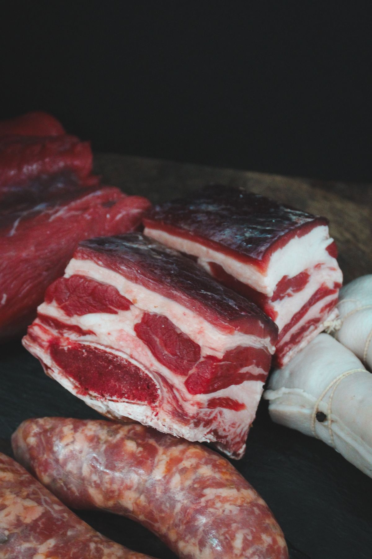 Raw pork ribs and sausages on a dark surface