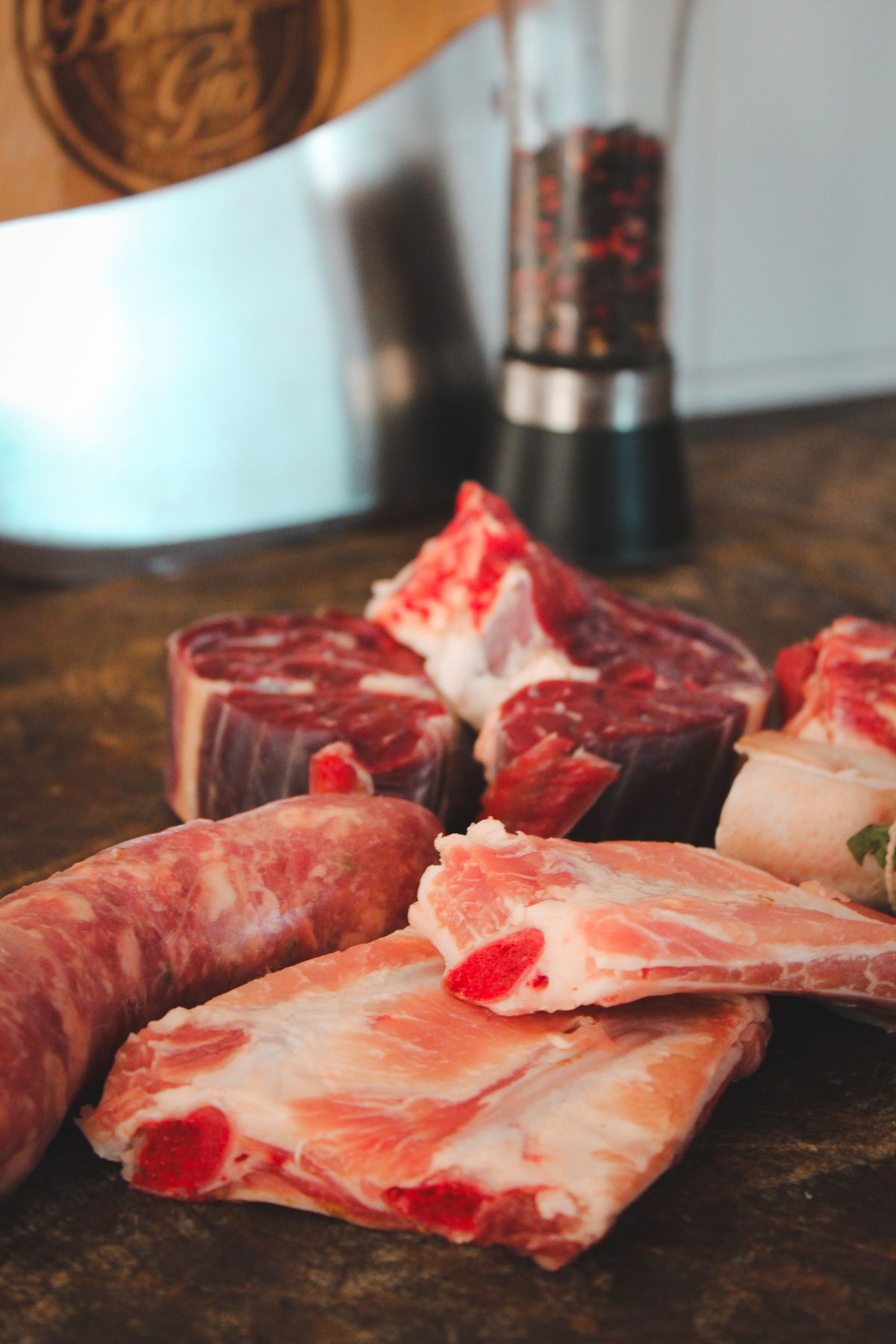 Assorted raw meat cuts and sausage on a kitchen table
