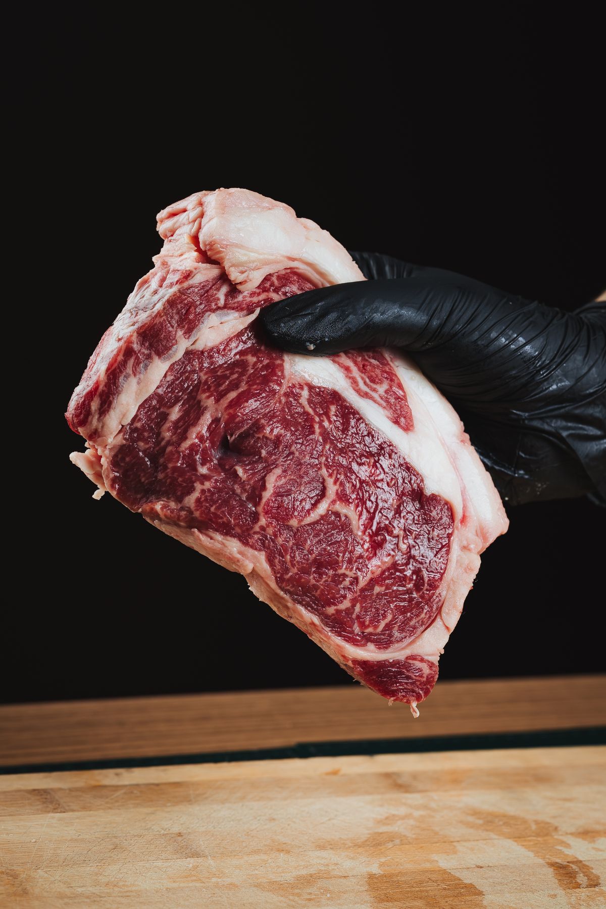Raw marbled ribeye steak on a black background